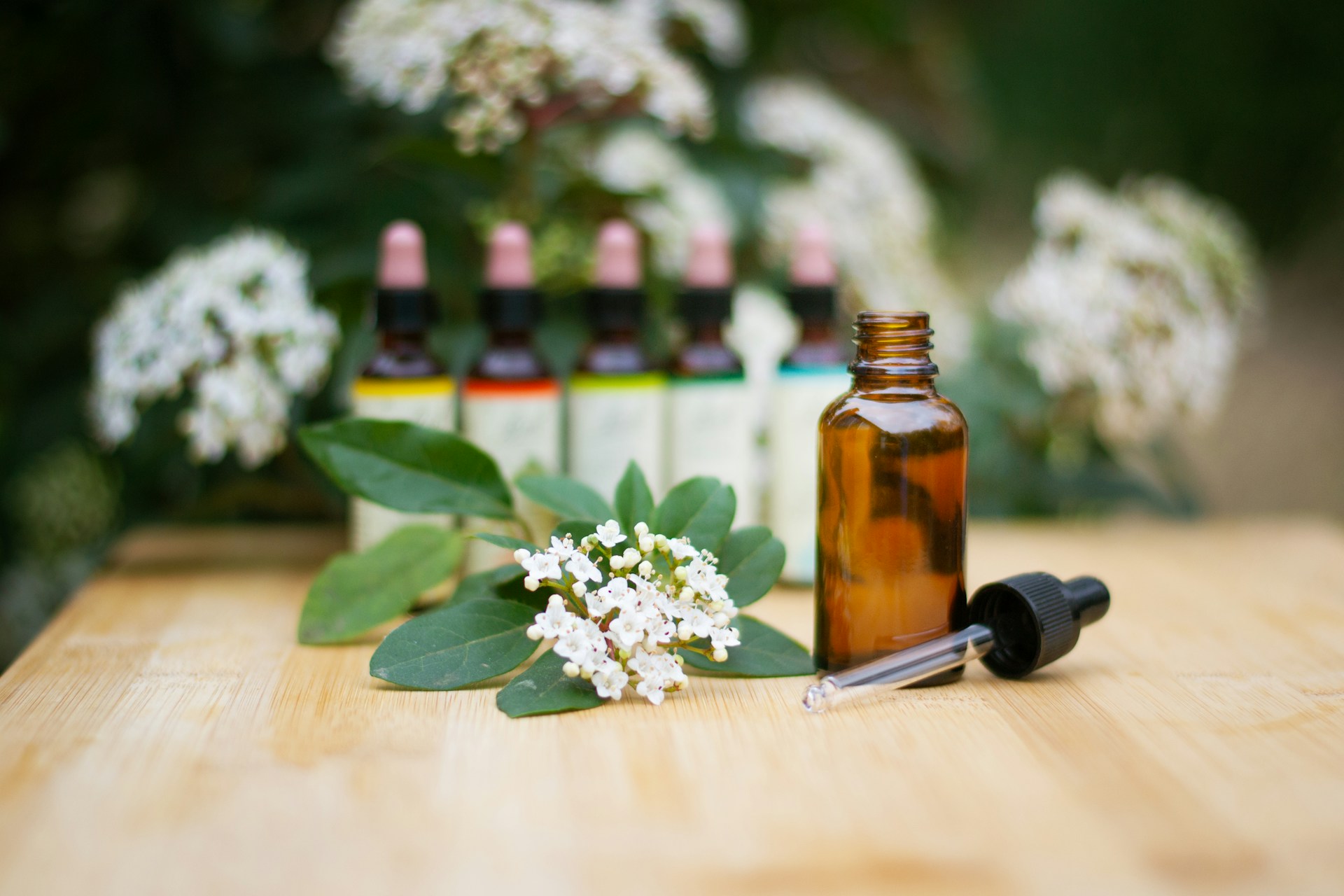 Bottles of essential oil with a white flower on a table